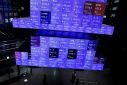 Visitors walk past Japan's Nikkei stock prices quotation board inside a conference hall in Tokyo