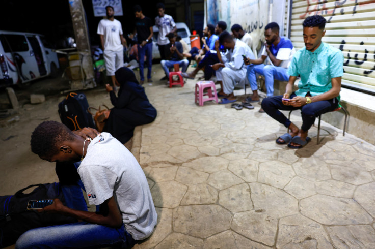 People wait for a bus before leaving to Egypt