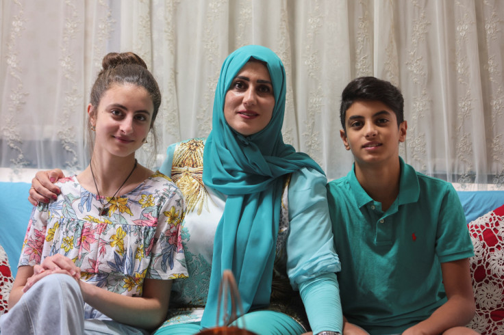 Public school teacher Claude Koteich poses for a picture with her son and daughter at their house in Deir Qubel