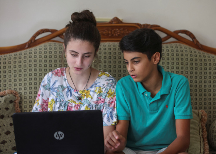 Public school teacher Claude Koteich's daughter and son sit together as they use a laptop at their house in Deir Qubel