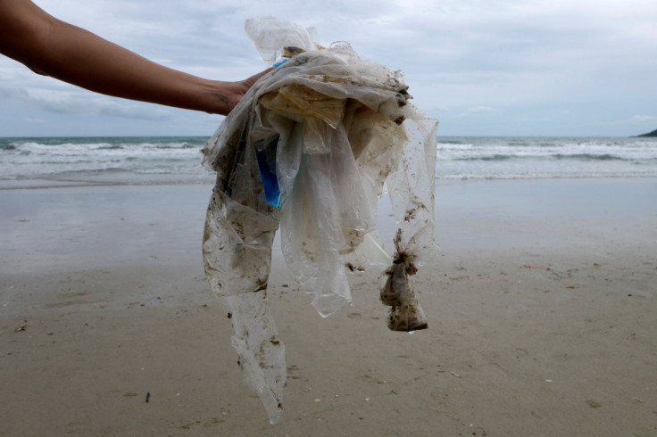 Tourist collects plastic items washed up by the sea at the Ao Phrao Beach, on the island of Ko Samet