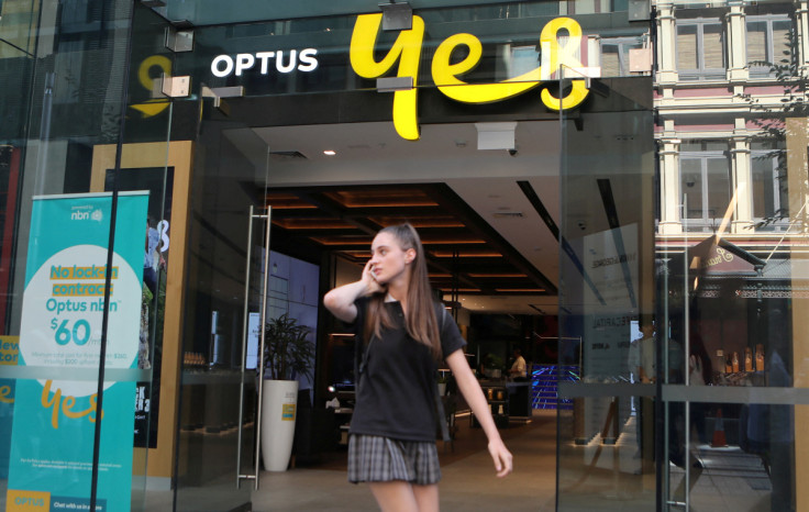 A woman uses her mobile phone as she walks past in front of an Optus shop in Sydney