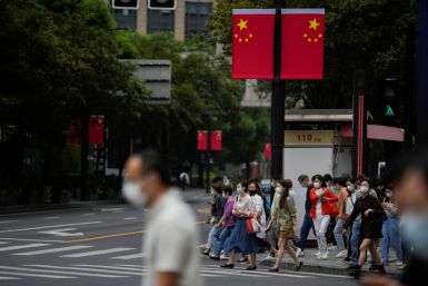 People wearing protective face masks cross a street under the Chinese flags, ahead of the Chinese National Day, following the COVID-19 outbreak, in Shanghai