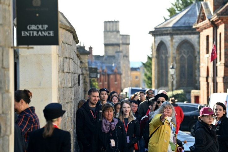 Long queues of tourists  stretched back along the narrow streets outside the castle's stately walls