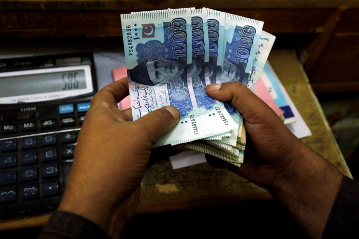 A trader counts Pakistani rupee notes at a currency exchange booth in Peshawar