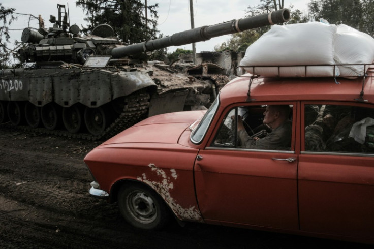 A civilian drives past an abandoned Russian tank in Kyrylivka