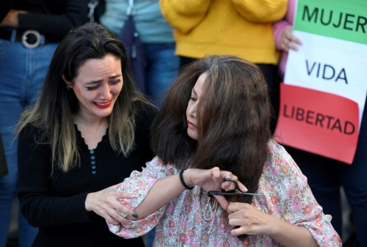 A protester cries as another cuts her hairs during a demonstration in support of Kurdish woman Mahsa Amini in Madrid