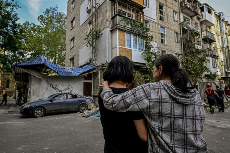 Women stand in front of a damaged residential building after shelling in the Ukrainian city of Mykolaiv, on October 1, 2022