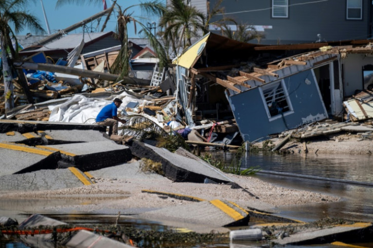 A man sits on a broken section of the Pine Island Road in the aftermath of Hurricane Ian in Matlacha, Florida on October 1, 2022