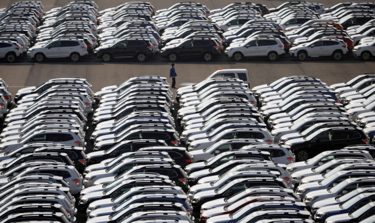 A worker is seen among newly manufactured cars awaiting export at port in Yokohama