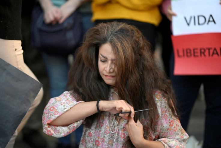 A protester cuts her hair during a demonstration in support of Mahsa Amini on October 1, 2022 in Madrid