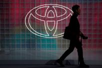A man walks past a Toyota logo at the Tokyo Motor Show
