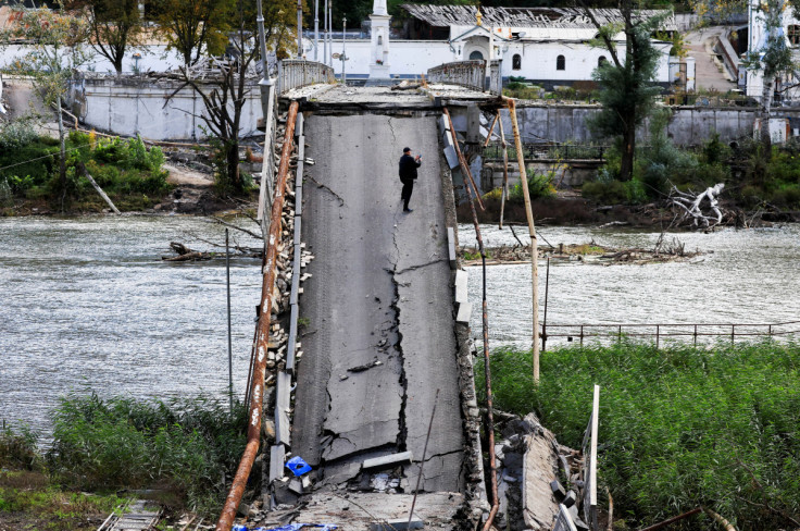 A Man uses his mobile phone as he stands on a bridge destroyed by a Russian Missile strike in Svyatohirsk