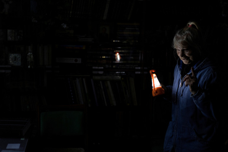 Olga Kobzar stands in her living room as she holds a battery light in her apartment in Saltivka neighbourhood of Kharkiv
