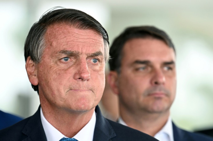Brazilian President and re-election candidate Jair Bolsonaro (L) listens to questions next to his son Flavio during a press conference at Planalto Palace in Brasilia, on October 4, 2022