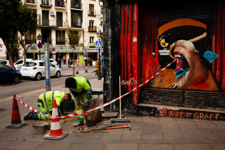 Workers do maintenance work next to a closed down bar in Madrid