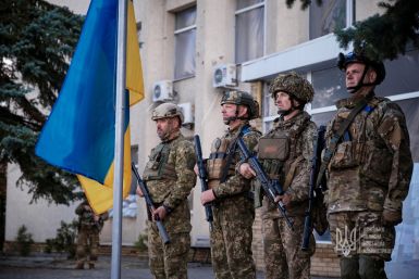 Ukrainian service members attend a flag raising ceremony in the town of Lyman