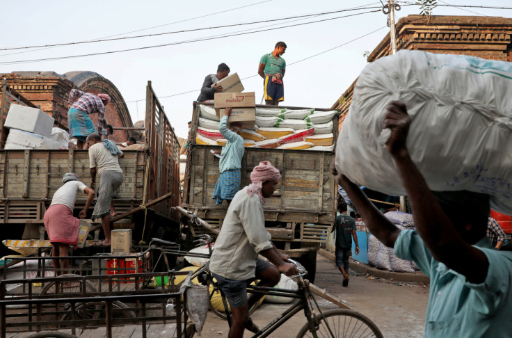 Labourers load consumer goods onto supply trucks at wholesale market in Kolkata