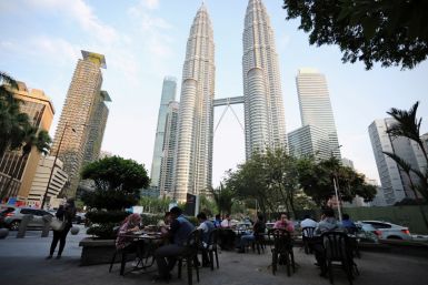 People dine in at a restaurant in front of Petronas Twin Towers, in Kuala Lumpur