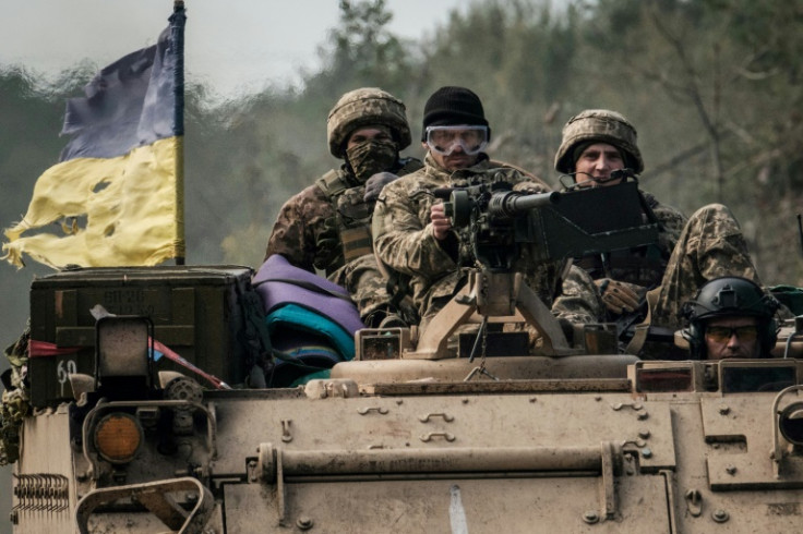 Ukrainian soldiers ride on an armoured vehicle near the recently retaken town of Lyman in Donetsk region