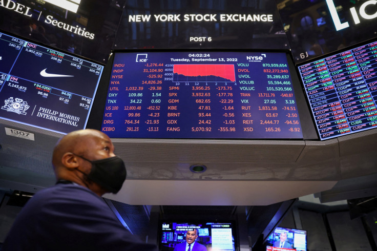 A trader stands beneath a screen on the trading floor displaying the Dow Jones Industrial Average at the New York Stock Exchange (NYSE) in Manhattan, New York City