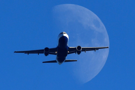 A passenger plane is seen with the moon behind as it flies over London