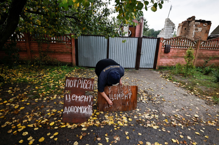 Valentyna Ivanivna, 58, prepares a second sign in which she is asking for help to provide her with cement, so that she can rebuild her house, in the newly recaptured town of Yarova