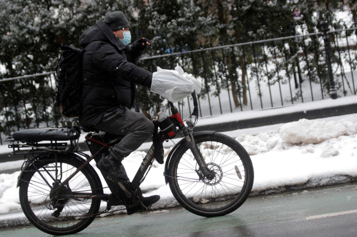 A food delivery person rides an electric bike during a snow storm in New York