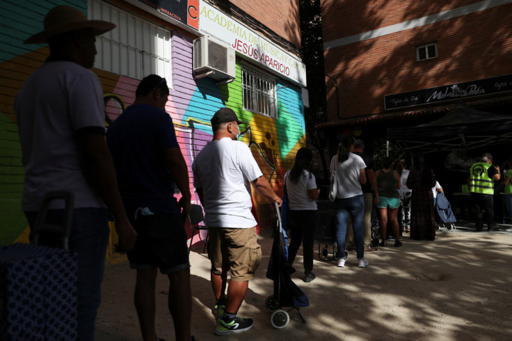 People Await their turn to receive basic food necessities from volunteers at the Aluche Mutual Support Network where hundreds queue every Saturday amidst soaring inflation and consumer price hikes, in the Aluche neighbourhood in Madrid