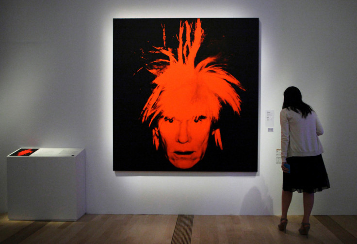 A woman looks at a self portrait by Andy Warhol during the media preview of an exhibition on his works in Singapore