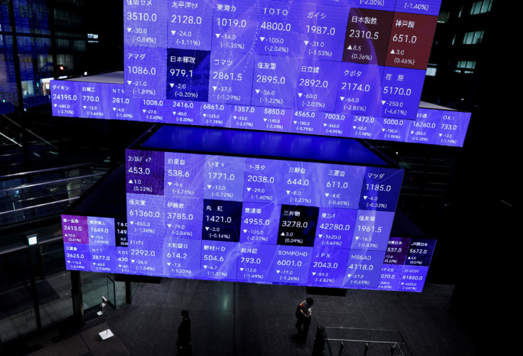 Visitors walk past Japan's Nikkei stock prices quotation board inside a conference hall in Tokyo