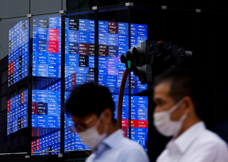 People pass by an electronic screen showing Japan's Nikkei share price index inside a conference hall in Tokyo