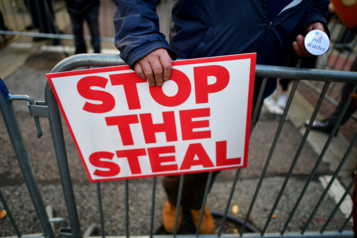 A supporter of President Donald Trump holds a sign stating "STOP THE STEAL" and a pin stating "Poll Watcher" in Philadelphia