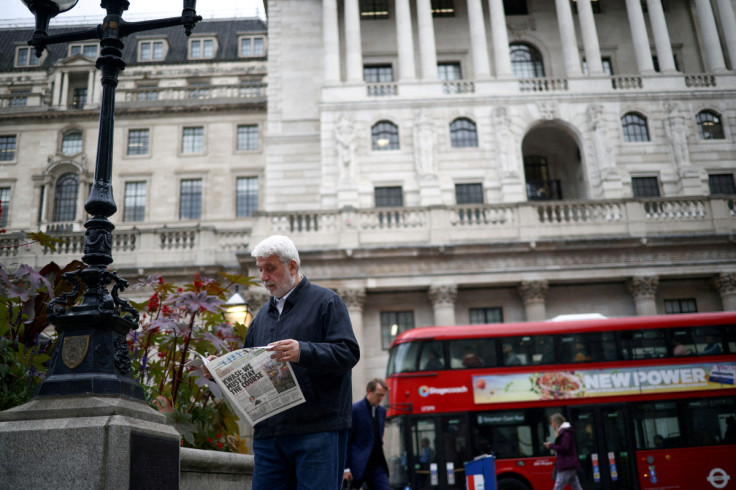 A person reads a newspaper outside the Bank of England in the City of London financial district in London
