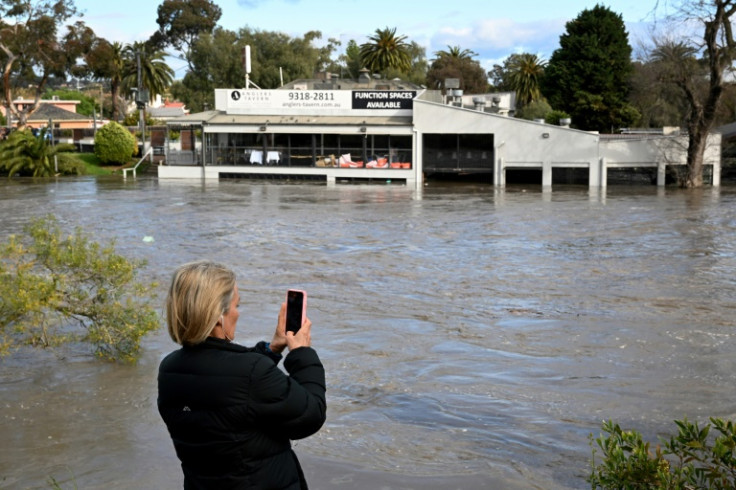 A woman films a flooded area in the Maribyrnong suburb of Melbourne on Friday
