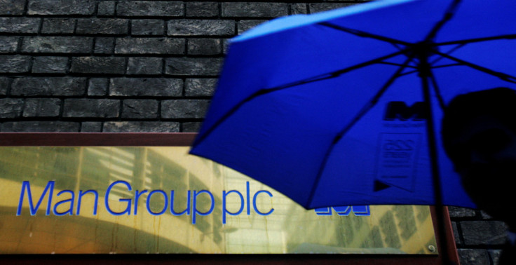 A man passes a sign for fund manager Man Group in London