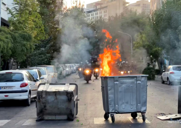 Iranian protesters have blocked roads with dumpter bins and even their own cars