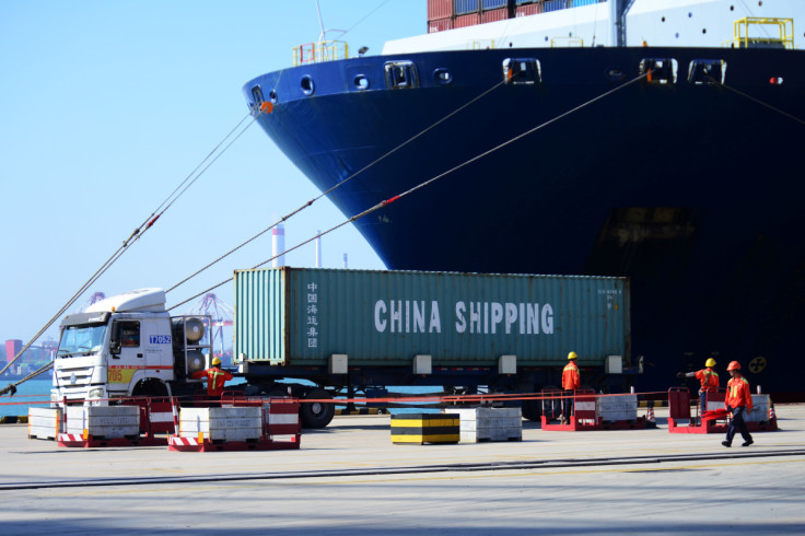 Truck transports a container next to a cargo vessel at a port in Qingdao, Shandong