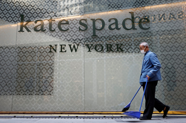 A cleaner walks past a store of the Kate Spade luxury fashion retailer in a shopping district in Beijing