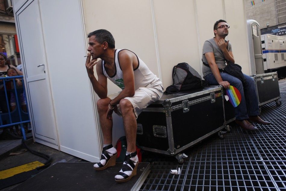 A man smokes with his high heel shoes on as he waits to take part in the annual race on high heels during Gay Pride celebrations in the quarter of Chueca in Madrid