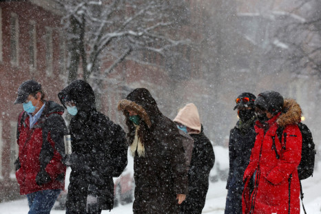 Pedestrians walk through falling snow during a winter storm in Boston