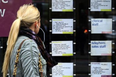 A woman passes notices for jobs in the window of a recruitment agency.
