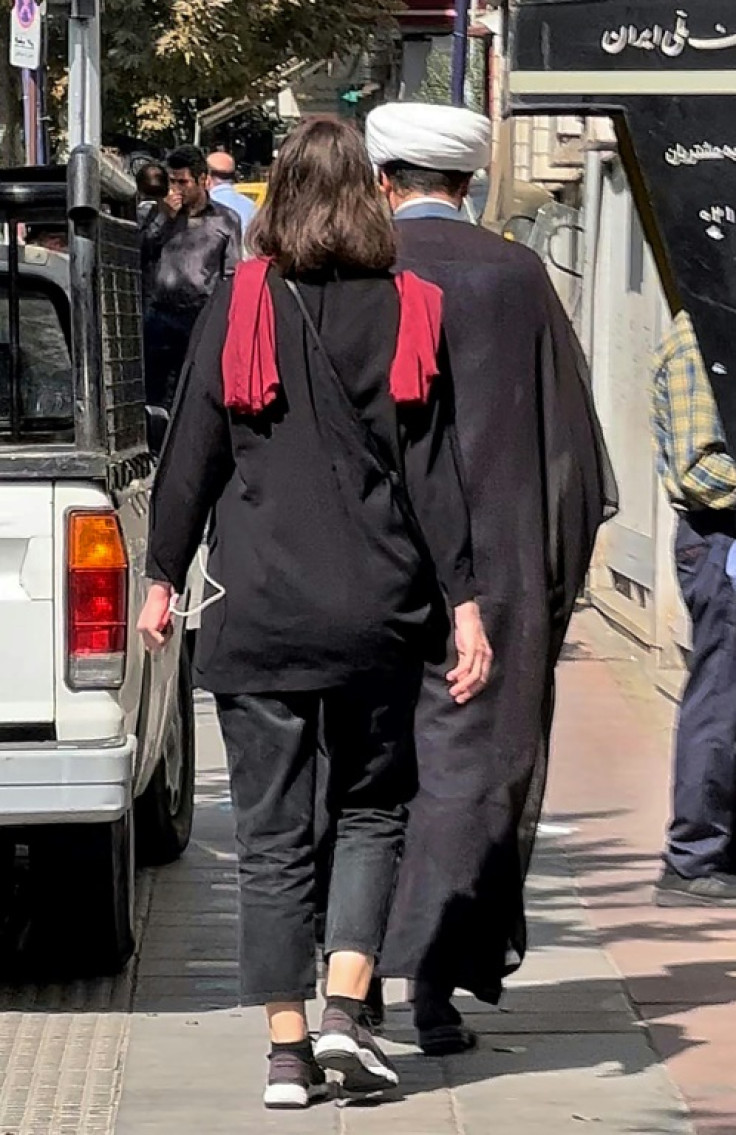 A woman walks on a street in Tehran without her hijab headscarf