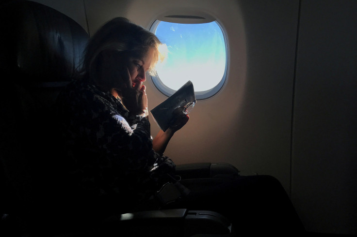 A woman reads while sitting in a business class seat on a flight from New York City to Washington D.C.