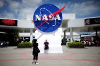 Tourists take pictures of a NASA sign at the Kennedy Space Center visitors complex in Cape Canaveral, Florida
