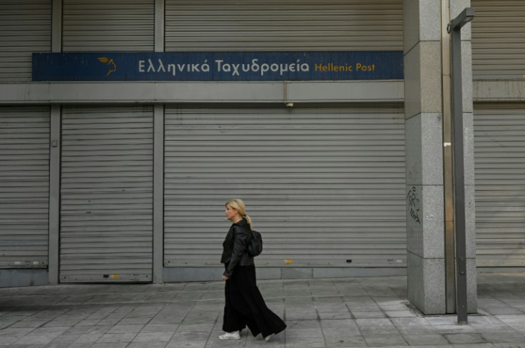 Seorang wanita berjalan melewati kantor pos yang tutup selama pemogokan 24 jam di Athena