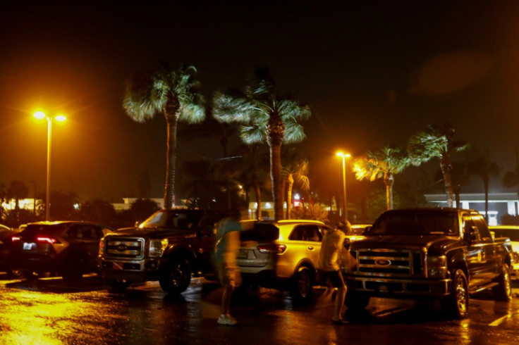 People fight the wind in a parking lot before Hurricane Nicole makes landfall in Jensen Beach, Florida