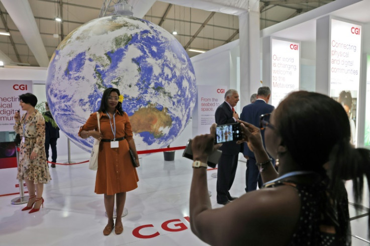 A woman poses for a picture in front of a globe inside the venue hosting the COP27 climate conference in Sharm el-Sheikh