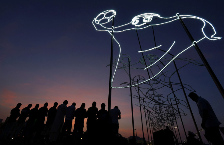 Believers pray at sunset next to the illuminated FIFA World Cup Qatar 2022 mascot La'eeb