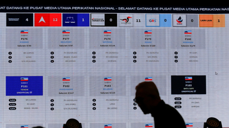 A man walks past a big screen showing live results of Malaysia's 15th general election, at a hotel in Shah Alam